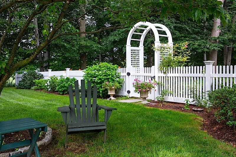 Welcoming chestnut-style vinyl fence with rose arbor and gate — Southington Rustic Fence Company